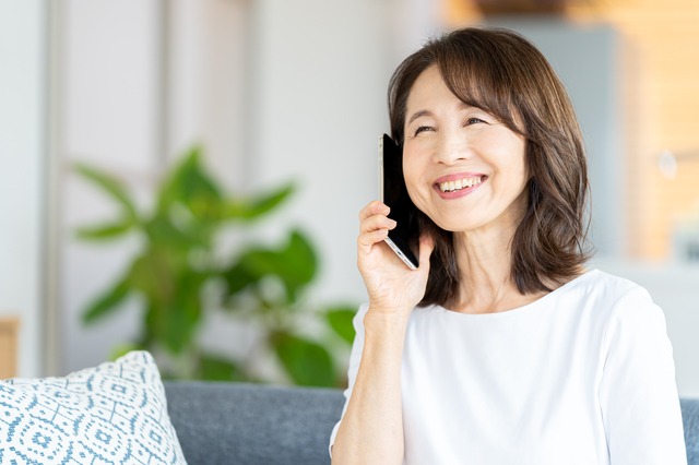 部屋で楽しそうに電話する女性、快気祝いのイメージ