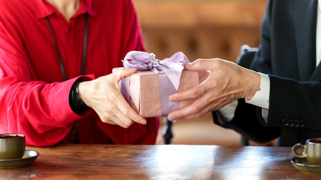 プレゼントを贈る年配の男性の手と受け取る女性の手