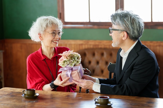 妻に花束とプレゼントを渡す夫