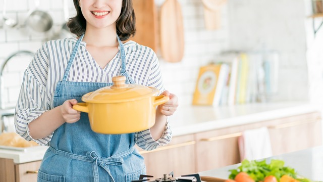 キッチンで黄色い鍋を持つ女性