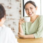 コーヒーを片手に談笑する女性2人