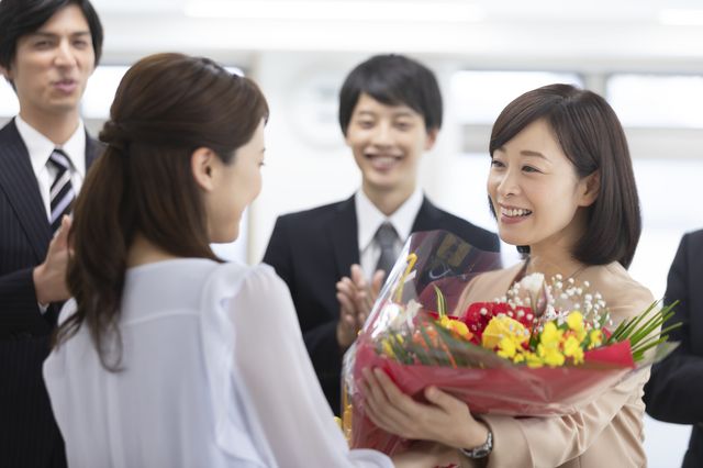 花束を渡す女性と拍手するスーツの男性