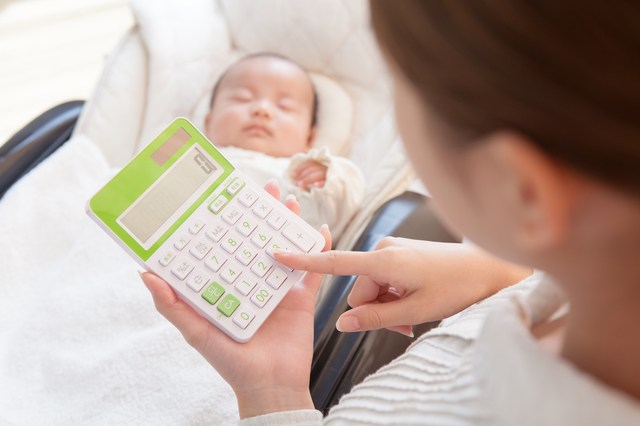 寝ている赤ちゃんと電卓で計算する母親　出産 内祝い 近所