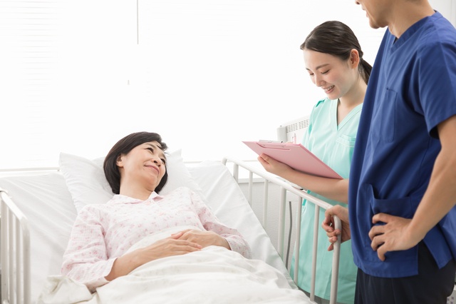 病院のベッドで話している女性患者と医師と看護師