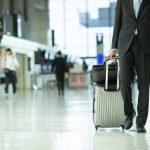 空港でスーツケースを持つスーツ姿の男性