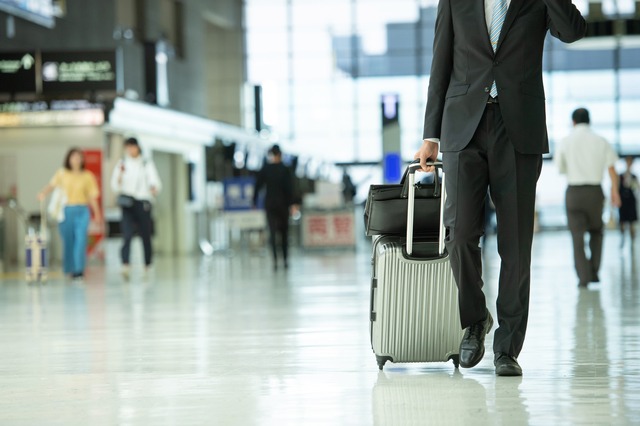 空港でスーツケースを持つスーツ姿の男性